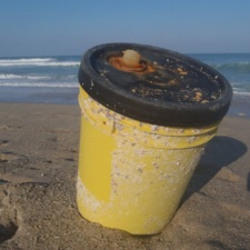 Plastic Pollution corosive plastic container on beach